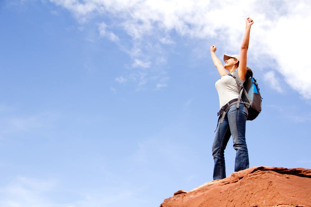 Woman at the top of a mountain conquering the world